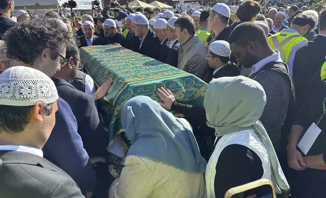 Fethullah Gulen's sister, Fazilet Korucuk, in blue head covering, touches his casket at a prayer service in Augusta, on Thursday, Oct. 24, in Augusta, New Jersey.(AP Photo/Mike Rubinkam)