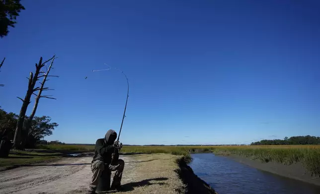 FILE - Gullah Geechee fisherman Ricky Wright casts his line as he fishes for bass in a marsh waterway with eroded banks on St. Helena Island, S.C., Sunday, Oct. 31, 2021. (AP Photo/Rebecca Blackwell, File)