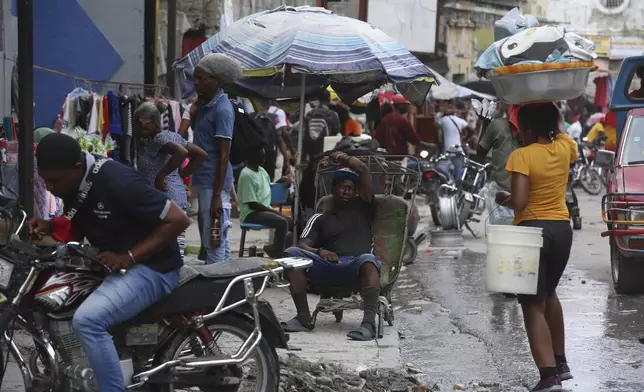 A man rests on a wheelbarrow on a street in Port-au-Prince, Haiti, Monday, Sept. 23, 2024. (AP Photo/Odelyn Joseph)