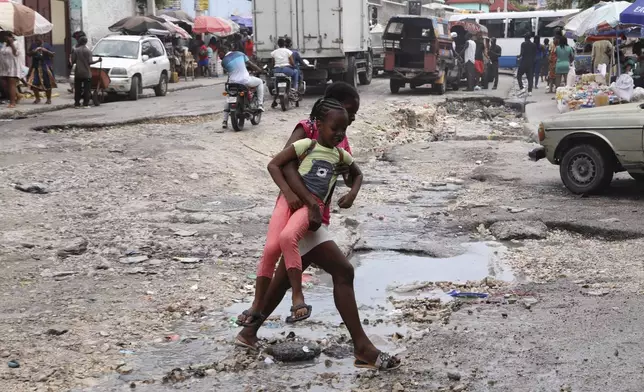 Pedestrians cross a street in downtown Port-au-Prince, Haiti, Monday, Sept. 23, 2024. (AP Photo/Odelyn Joseph)