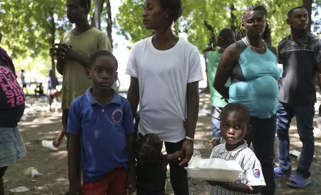 People displaced by armed attacks receive food from a nongovernmental organization in Saint-Marc, Haiti, Sunday, Oct. 6, 2024. (AP Photo/Odelyn Joseph)