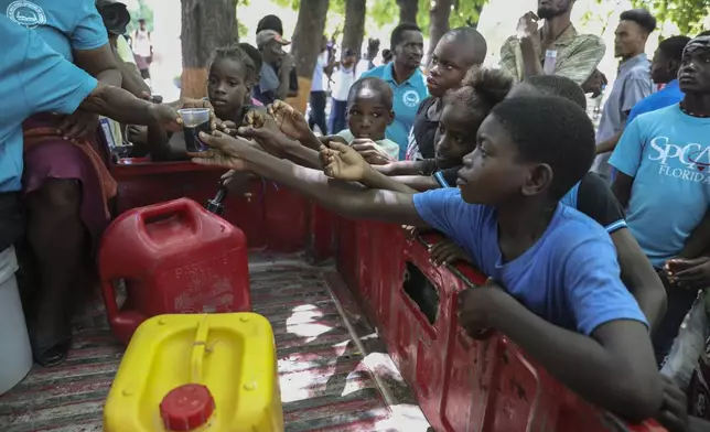 People displaced by armed attacks receive food from a nongovernmental organization in Saint-Marc, Haiti, Sunday, Oct. 6, 2024. (AP Photo/Odelyn Joseph)