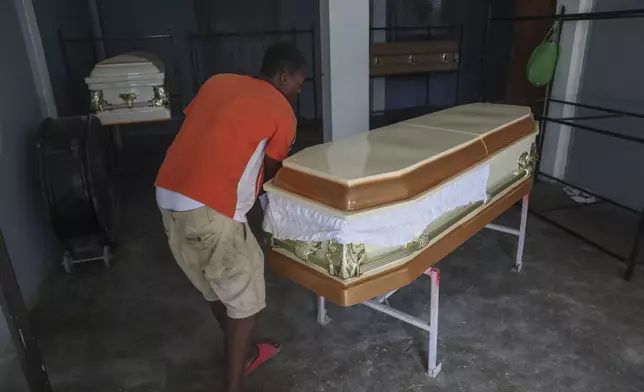 Morgue workers move an empty coffin in Pont-Sonde, Haiti, Tuesday, Oct. 8, 2024, days after a deadly gang attack on the town. (AP Photo/Odelyn Joseph)