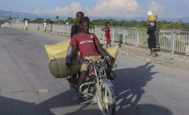 People cross a bridge in Pont-Sonde, Haiti, Tuesday, Oct. 8, 2024, days after a deadly gang attack in the town. (AP Photo/Odelyn Joseph)