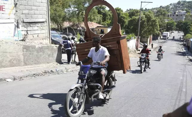 A resident, with a dresser attached to the back of his motorbike, flees his home escaping gang violence in the Solino neighborhood of Port-au-Prince, Haiti, Saturday, Oct. 26, 2024. (AP Photo/Odelyn Joseph)