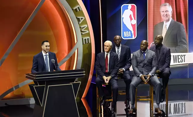 Jonnie West, left, speaks during his late father Jerry West's enshrinement in the Basketball Hall of Fame as, from second from left to right, Pat Riley, Bob McAdoo, Magic Johnson and James Worthy look on Sunday Oct. 13, 2024, in Springfield, Mass. (AP Photo/Jessica Hill)