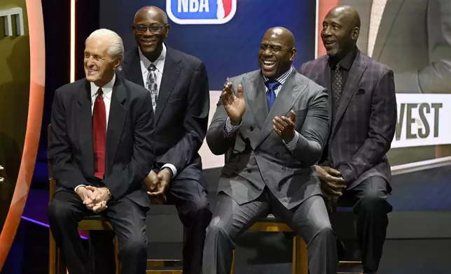 Magic Johnson, second from right reacts as Jonnie West speaks during his father Jerry West's enshrinement in the Basketball Hall of Fame, as he sits with from left, Pat Riley, Bob McAdoo and James Worthy, Sunday Oct. 13, 2024, in Springfield, Mass. (AP Photo/Jessica Hill)