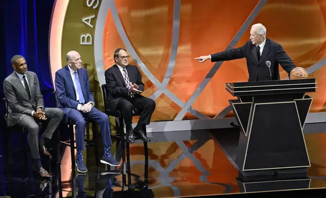 Doug Collins, right, points to his presenters, from left to right, Grant Hill, Billy Cunningham and Jerry Reinsdorf during his enshrinement in the Basketball Hall of Fame, Sunday Oct. 13, 2024, in Springfield, Mass. (AP Photo/Jessica Hill)