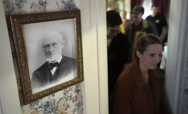 Visitors walk past a framed photograph of murder victim Andrew Borden, left, Wednesday, Oct. 16, 2024, while touring the Lizzie Borden House, site of an 1892 double axe murder, in Fall River, Mass. (AP Photo/Steven Senne)