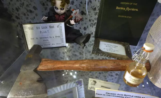 An axe, front, is displayed near a figurine, left, in a display case, Wednesday, Oct. 16, 2024, at the Lizzie Borden House, site of an 1892 double axe murder, in Fall River, Mass. (AP Photo/Steven Senne)