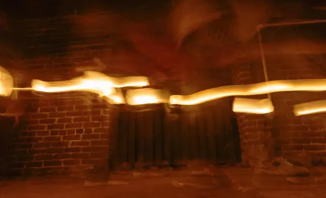 In this image taken with a slow shutter speed, people use lanterns to light their way on a tour of underground passages on Thursday, Oct. 17, 2024, in Portland, Ore. (AP Photo/Jenny Kane)