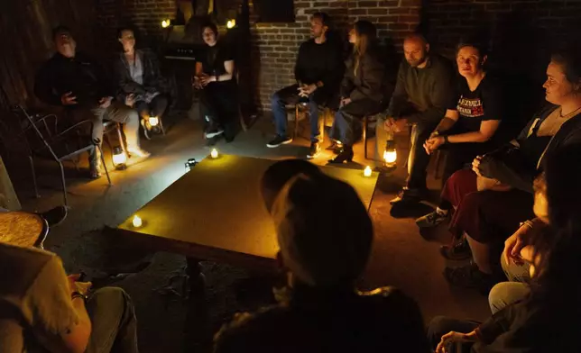 Treva Smith, second from right, looks up as Kate Nelson, right, listens to stories told by Natasha Cimmiyotti, third from left, before a tour of underground passages on Thursday, Oct. 17, 2024, in Portland, Ore. (AP Photo/Jenny Kane)