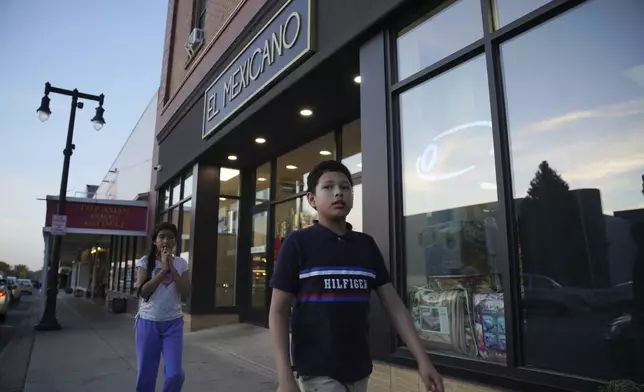 Children walk past El Mexicano, a grocery store in Worthington, Minn., on Sunday Oct. 20, 2024. (AP Photo/Jessie Wardarski)