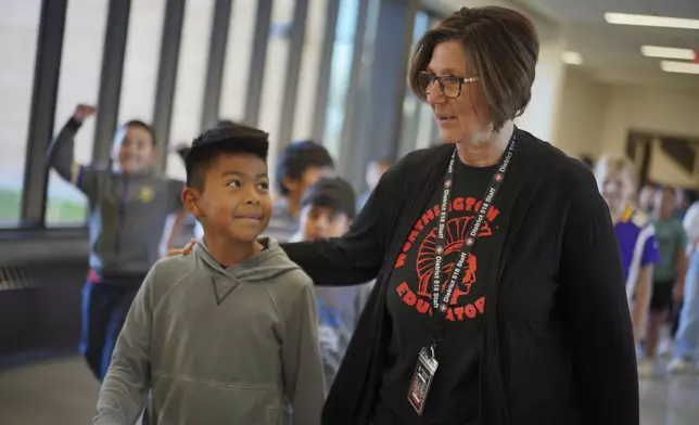 Suzy Brandner, right, who has taught in Worthington for 34 years, talks with a student walking down the hall at the intermediate school, which serves grades three through five, in Worthington, Minn., on Tuesday, Oct. 22, 2024. (AP Photo/Jessie Wardarski)