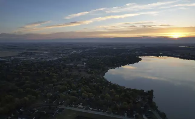 The sun rises over Okabena Lake and the town of Worthington, Minn., on Tuesday, Oct. 22, 2024. (AP Photo/Jessie Wardarski)