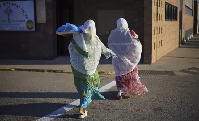 Members of the Ethiopian Orthodox Tewahedo Church carry food across the street on Sunday, Oct. 20, 2024, in Worthington, Minn. (AP Photo/Jessie Wardarski)