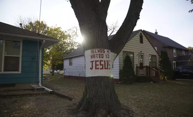 A religious sign is carved into a tree in a neighborhood of Worthington, Minn., on Monday, Oct. 21, 2024. (AP Photo/Jessie Wardarski)