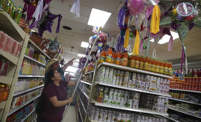 Cristina Cabrera, who fled poverty in Central America three years ago, helps a customer pick a piñata at El Mexicano, a local grocery in downtown Worthington, Minn., on Saturday, Oct. 19, 2024. (AP Photo/Jessie Wardarski)