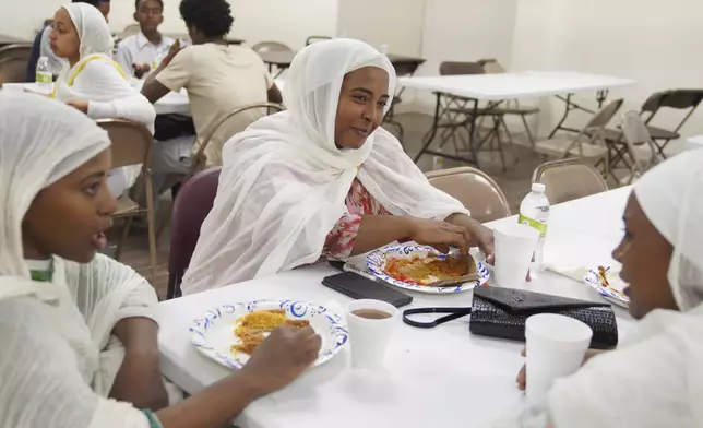 Mintamir Endanew, left, and other women at the Ethiopian Orthodox Tewahedo Church enjoy a post-liturgy lunch of pancake-like injera bread on Sunday, Oct. 20, 2024, in Worthington, Minn. (AP Photo/Jessie Wardarski)