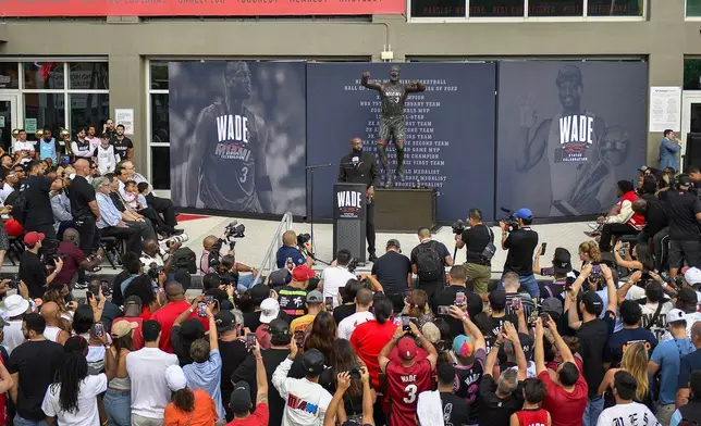 Former Miami Heat NBA basketball player Dwyane Wade, center, speaks during his statue unveiling ceremony outside the Kaseya Center, Sunday, Oct. 27, 2024, in Miami, Fla. (AP Photo/Michael Laughlin)