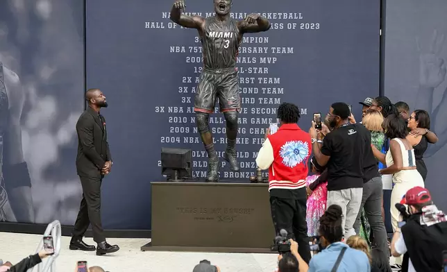 Former Miami Heat NBA basketball player Dwyane Wade, upper left, looks at a bronze statue of himself during a statue unveiling ceremony outside the Kaseya Center, Sunday, Oct. 27, 2024, in Miami, Fla. (AP Photo/Michael Laughlin)