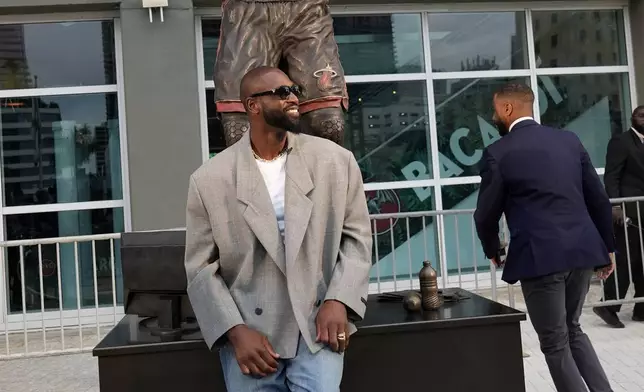 Former Miami Heat player Dwyane Wade stands next to his statue outside of the Kaseya Center before an NBA basketball game between the Miami Heat and the Detroit Pistons, Monday, Oct. 28, 2024, in Miami. (AP Photo/Lynne Sladky)