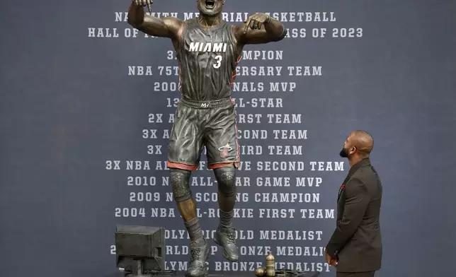 Former Miami Heat NBA basketball player Dwyane Wade looks at a bronze statue in his image during its unveiling ceremony outside Kaseya Center, Sunday, Oct. 27, 2024, in Miami, Fla. (AP Photo/Michael Laughlin)