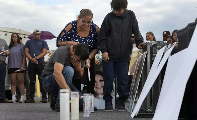 Daniel Delgado kneels in front of a photo of his wife, Monica Hernandez, who died at Impact Plastics during flooding caused by Hurricane Helene, while being comforted by his sister-in-law, Guadalupe Hernandez-Corona, during a vigil for victims of the tragedy in Erwin, Tenn., on Thursday, Oct. 3, 2024. (AP Photo/Jeff Roberson)