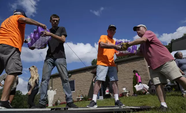 Volunteers unload cases of water and other donated supplies outside St. Michael the Archangel Catholic church in the aftermath of Hurricane Helene in Erwin, Tenn., on Thursday, Oct. 3, 2024. (AP Photo/Jeff Roberson)