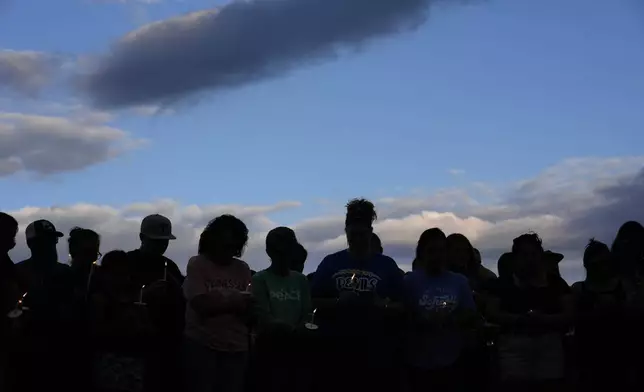 Mourners hold candles and stand silently during a vigil for victims of the Impact Plastics tragedy in the aftermath of Hurricane Helene in Erwin, Tenn., on Thursday, Oct. 3, 2024. (AP Photo/Jeff Roberson)