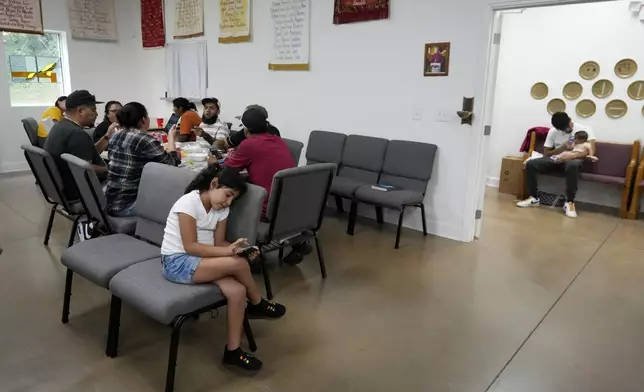 Adults gather at a table for a meal as life goes on around them inside St. Michael the Archangel Catholic church in the aftermath of Hurricane Helene Friday, Oct. 4, 2024, in Erwin, Tenn. (AP Photo/Jeff Roberson)