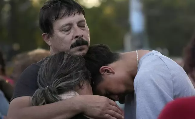 Daniel Delgado, top, is comforted by his 16-year-old son Angel Delgado, right, as he mourns the loss of his wife and Angel's mother, Monica Hernandez, who died at Impact Plastics during flooding caused by Hurricane Helene in Erwin, Tenn., on Thursday, Oct. 3, 2024. (AP Photo/Jeff Roberson)