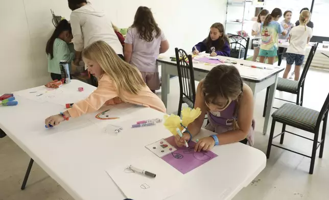 Seven-year-old Reyna Weissman, right, participates in arts and crafts, Monday, Oct. 7, 2024, at the Project:Camp pop-up daycamp for families impacted by Hurricane Helene in Brevard, N.C. (AP Photo/Gabriela Aoun Angueira)