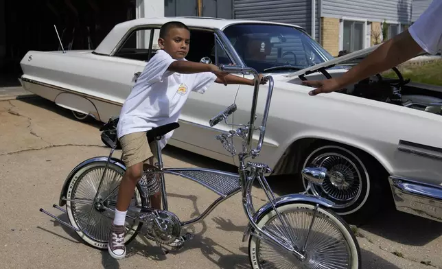 Seven-year-old Daniel Marquez sits on his chrome lowrider bike, custom-built by himself and family friends in memory of his late father Alberto, a longtime member of lowrider car clubs, Saturday, Sept. 14, 2024, at his home in Frankfort, Ill. (AP Photo/Erin Hooley)