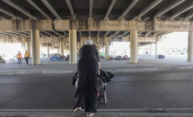 People living in a homeless encampment pick up belongings after Louisiana State police gave instructions for them to move to a different pre-designated location as they perform a sweep in advance of a Taylor Swift concert in New Orleans, Wednesday, Oct. 23, 2024. (AP Photo/Gerald Herbert)