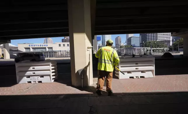 A Louisiana Department of Transportation and Development employee paints a support under an elevated expressway that was cleared out after Louisiana State police gave instructions to people living in a homeless encampment there to move to a different pre-designated location as they perform a sweep in advance of a Taylor Swift concert in New Orleans, Wednesday, Oct. 23, 2024. (AP Photo/Gerald Herbert)