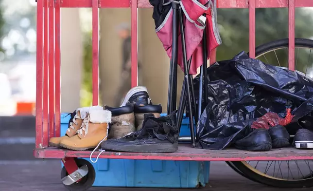 Possessions sit on a cart as Louisiana State police give instructions to people living in a homeless encampment to move to a different pre-designated location as they perform a sweep in advance of a Taylor Swift concert in New Orleans, Wednesday, Oct. 23, 2024. (AP Photo/Gerald Herbert)