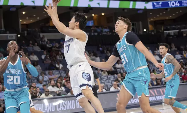 Memphis Grizzlies guard Yuki Kawamura (17), of Japan, shoots defended by Charlotte Hornets forward Harry Giles, forward Tidjane Salaun (31), of France, and guard K.J. Simpson (25) in the second half of a preseason NBA basketball game Thursday, Oct. 10, 2024, in Memphis, Tenn. (AP Photo/Nikki Boertman)