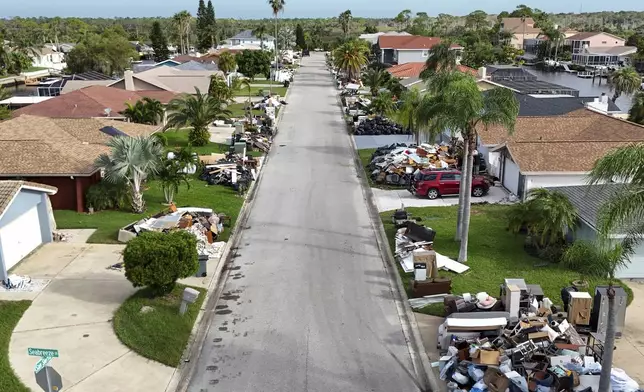 Debris from homes flooded in Hurricane Helene sits curbside as Hurricane Milton approaches on Tuesday, Oct. 8, 2024, in Port Richey, Fla. (AP Photo/Mike Carlson)