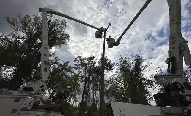 Contractors for Duke Energy rebuild destroyed electrical lines near the Swannanoa River in Asheville, N.C., Friday, Oct. 4, 2024. (AP Photo/Jeff Amy)