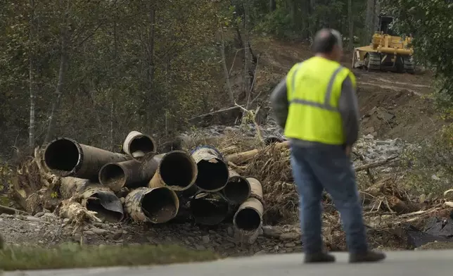 Electrical contract worker Matthew Tipton looks over the remnants of a waterline serving Asheville, N.C., downstream from North Fork Reservoir, a main source of water for the city, Wednesday, Oct. 2, 2024, after the line was destroyed during Hurricane Helene in Black Mountain, N.C. (AP Photo/Jeff Roberson)