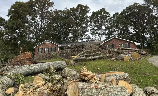 Cut up sections of a tree sit on front of a house Friday, Oct. 4, 2024, in the Oak Forest neighborhood of Asheville, N.C., in the aftermath of Hurricane Helene. (AP Photo/Jeff Amy)