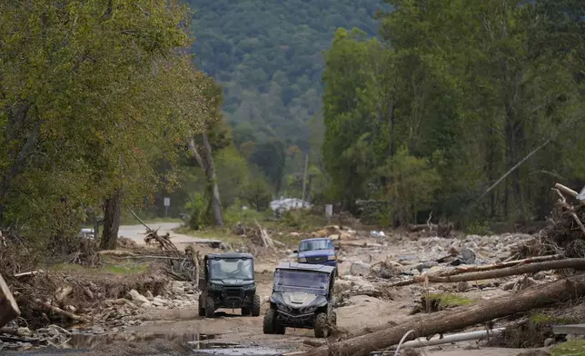 Vehicles roll along on a washed up road in the aftermath of Hurricane Helene, Thursday, Oct. 3, 2024, in Pensacola, N.C. (AP Photo/Mike Stewart)