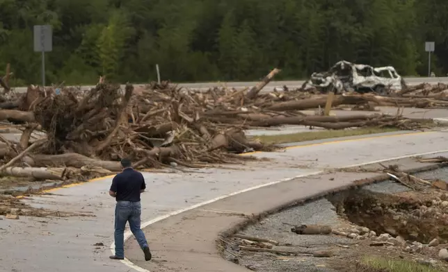 A person walks on Interstate 26 as debris covers the roadway in the aftermath of Hurricane Helene, Friday, Oct. 4, 2024, in Erwin, Tenn. (AP Photo/Jeff Roberson)