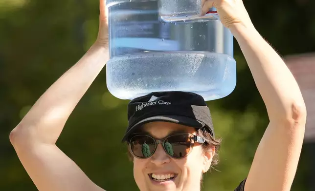 Lindsay Rust carries a jug of fresh water after filling up at a distribution site in the aftermath of Hurricane Helene Wednesday, Oct. 2, 2024, in Asheville, N.C. (AP Photo/Jeff Roberson)