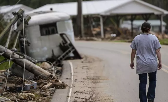 A woman walks to her damaged home in the aftermath of Hurricane Helene, Thursday, Oct. 3, 2024, in Pensacola, N.C. (AP Photo/Mike Stewart)