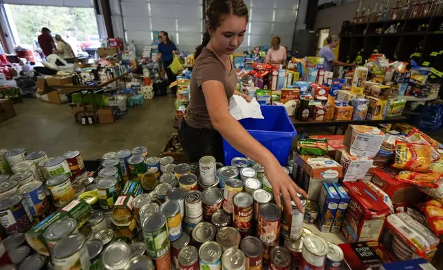 A volunteer gathers food for families at the volunteer fire station in the aftermath of Hurricane Helene, Thursday, Oct. 3, 2024, in Pensacola, N.C. (AP Photo/Mike Stewart)