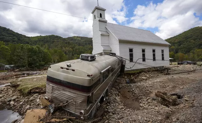 A bus pushed by flood waters rests against Laurel Branch Baptist church in the aftermath of Hurricane Helene, Thursday, Oct. 3, 2024, in Pensacola, N.C. (AP Photo/Mike Stewart)