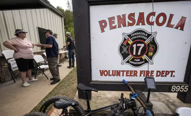 People speak outside the volunteer fire house in the aftermath of Hurricane Helene, Thursday, Oct. 3, 2024, in Pensacola, N.C. (AP Photo/Mike Stewart)