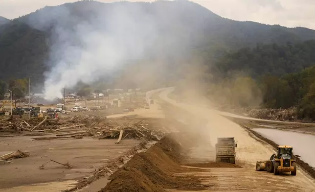 Heavy machinery is used to clear Interstate 26 as debris is burned in the background following Hurricane Helene Friday, Oct. 4, 2024, in Erwin, Tenn. (AP Photo/Jeff Roberson)